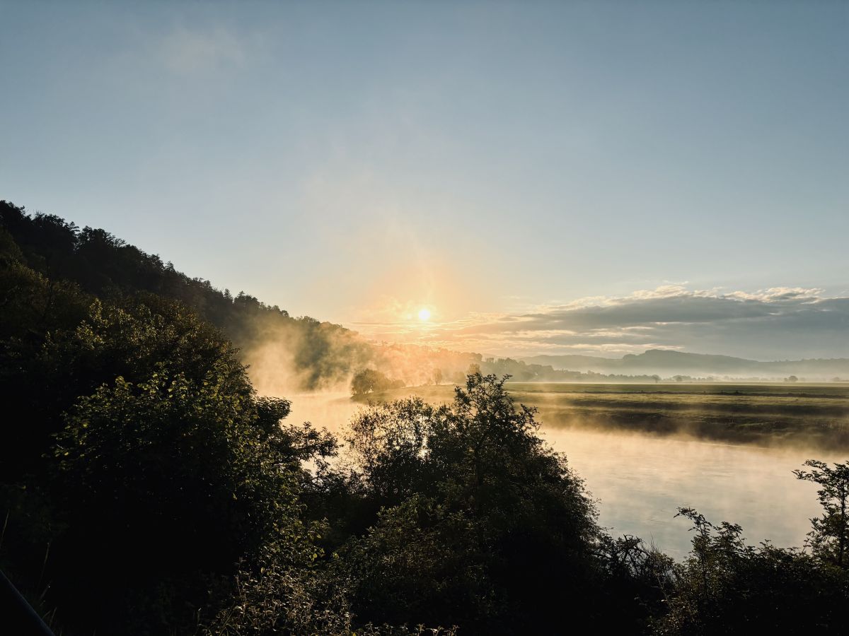 Morgendliche Nebelschwaden über der Weser und dem Sonnenaufgang im Hintergrund